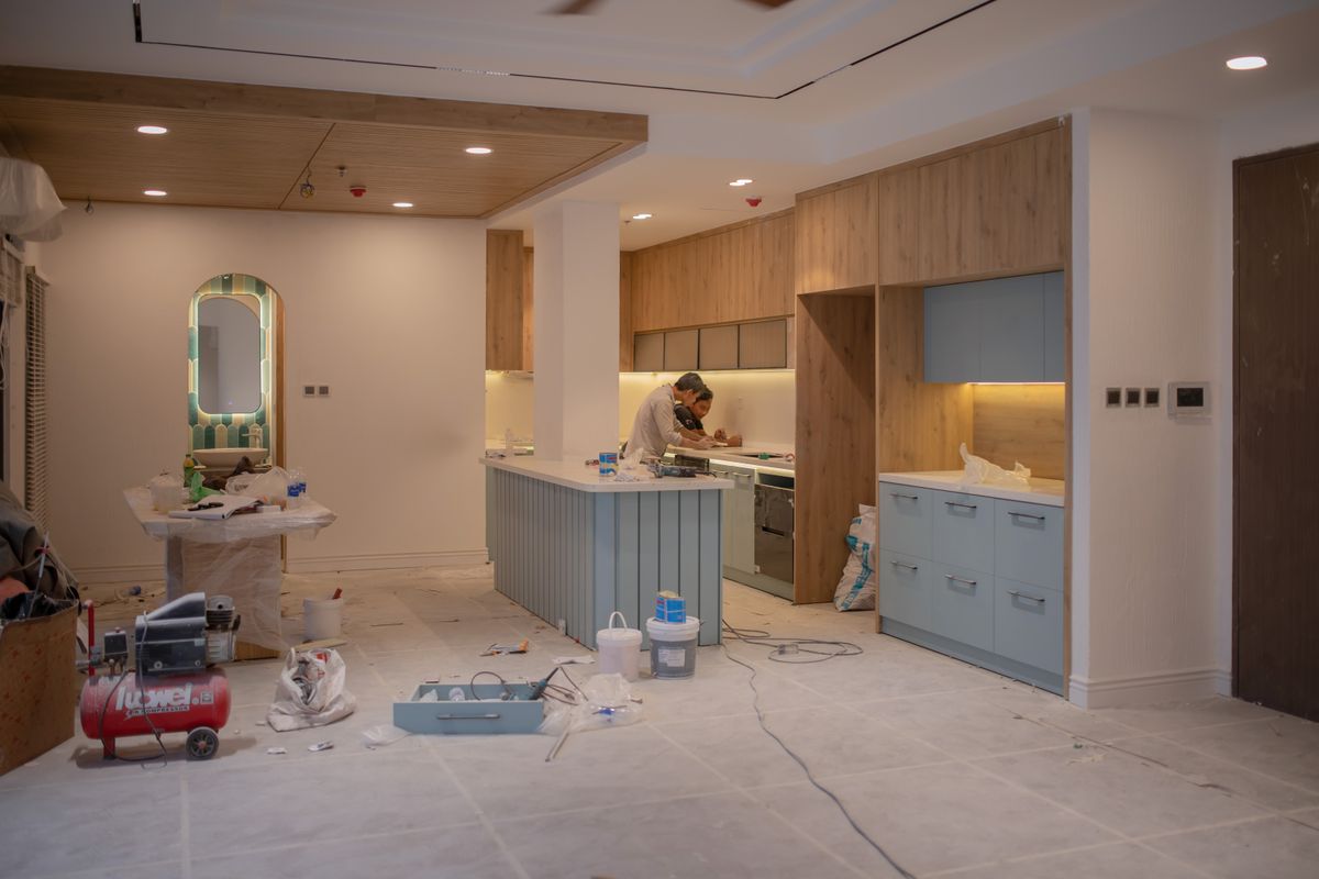 Kitchen cabinets being spray-painted a warm white with doors removed and labeled