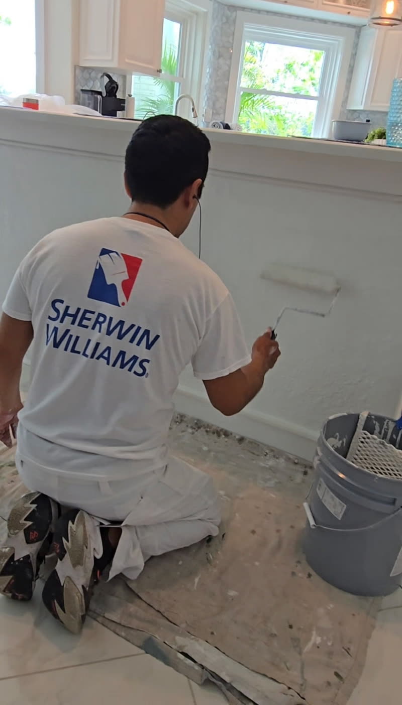Ivan's Painting painter rolling fresh white paint on an interior wall with floors protected
